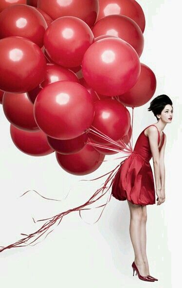 Woman in red with dozens of red balloons